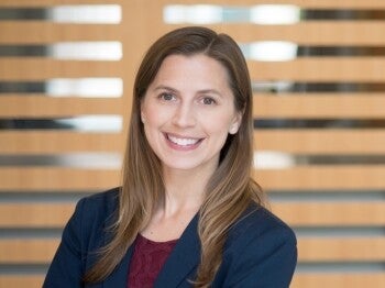 Kristen Grauman smiling in front of wood slat dividing wall.
